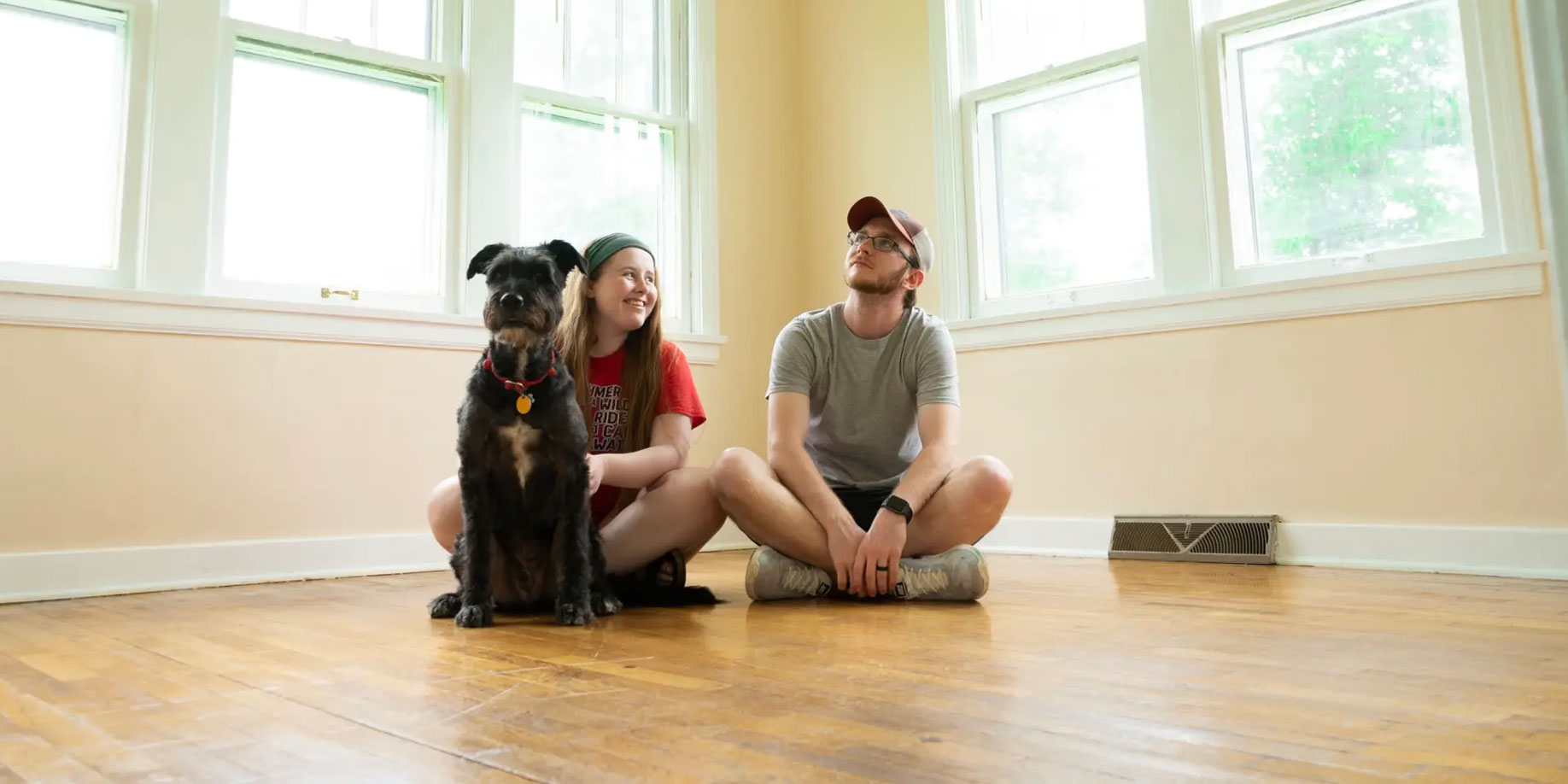 A couple sitting on the floor with their dog in the middle of moving